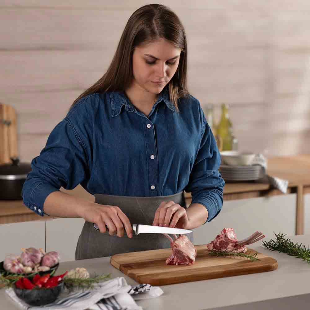 woman frenching rack of lamb with boning knife - Robins Kitchen